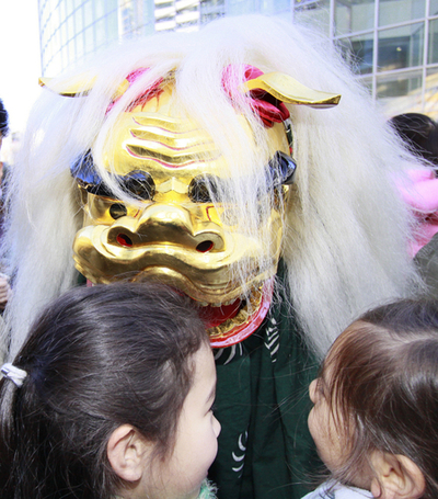 新年の幸運を願って獅子舞がガブリ、東京
