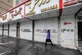 イランの首都テヘランで、閉鎖された店舗の前を歩く女性（2022年12月5日撮影）。(c)ATTA KENARE / AFP