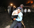 パキスタンのイスラマバード（Islamabad）で、爆弾による大きな爆発が発生し、炎上したマリオットホテル（Marriott Hotel、奥）から被害に遭った人を運び出す警官（2008年9月20日撮影）。(c)AFP/Aamir QURESHI