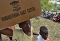 ハイチ・ポルトープランス（Port-au-Prince）の避難民キャンプで、食糧の入った箱を運ぶ子ども（2010年1月19日撮影）。(c)AFP/Luis Acosta
