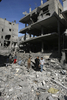 パレスチナ自治区ガザ市（Gaza City）郊外Sheikh Radwanで、イスラエル軍による空爆で破壊された建物のがれきを見るパレスチナ人（2009年1月14日撮影）。(c)AFP/MAHMUD HAMS