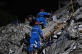 トルコ・イズミルで、倒壊した建物のがれきから生存者を捜索する救助隊員ら（2020年10月31日撮影）。(c)OZAN KOSE / AFP