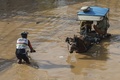 インドネシア・西ジャワ州バンドンの洪水した通りですれ違う馬車と自転車。豪雨で川が氾濫し、多くの家屋が浸水した（2025年3月16日撮影）。(c)Timur Matahari / AFP