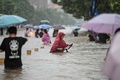 中国・河南省鄭州市で、冠水した道路を歩く人（2021年7月20日撮影）。(c)STR / AFP