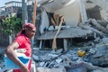 地震に見舞われたハイチ南西部レカイで、損壊した住宅の前を歩く女性（2021年8月15日撮影）。(c)Reginald LOUISSAINT JR / AFP