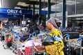 荷物仕分け機器が故障したフランス・オルリ空港で、荷物カートの横を歩く乗客（2023年8月3日撮影）。(c)STEFANO RELLANDINI / AFP