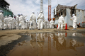 東京電力（TEPCO）は26日、福島第1原子力発電所の敷地内を報道陣に公開した。写真は第1原発4号機のそばを歩く報道陣と東電従業員（2012年5月26日撮影）。(c)AFP/POOL/Tomohiro Ohsumi