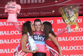 第96回ジロ・デ・イタリア（2013 Giro d&apos;Italia）、第2ステージ（イスキアからフォリーオ、17.4キロメートル、チームタイムトライアル）。総合首位（マリア・ローザ）を獲得し、表彰台でキスの祝福を受けるスカイ（Sky Pro Cycling）のサルヴァトーレ・プッチオ（Salvatore Puccio、中央、2013年5月5日撮影）。(c)AFP/LUK BENIES