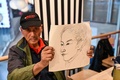 中国・上海にあるイケアのカフェテリアで別の参加者の似顔絵を見せる男性（2023年12月5日撮影）。(c)Hector RETAMAL / AFP