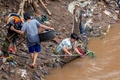 豪雨による洪水に見舞われたインドネシアの首都ジャカルタで、食器などを洗う人々（2020年1月3日撮影）。(c)BAY ISMOYO / AFP