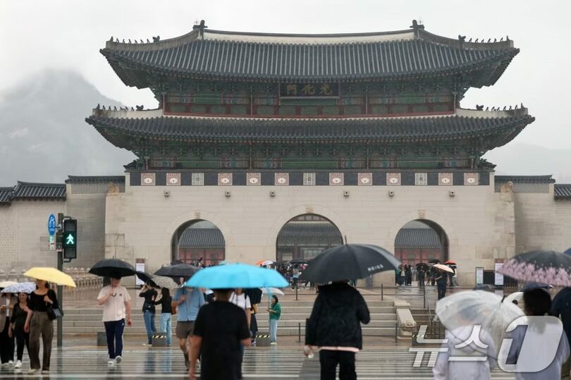 傘を差して歩く市民と外国人観光客ら(c)news1