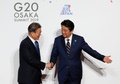 大阪で開催中の20か国・地域（G20）首脳会議の歓迎行事で、韓国の文在寅（ムン・ジェイン）大統領（左）を迎える安倍晋三首相（右、2019年6月28日撮影）。(c)KIM KYUNG-HOON / POOL / AFP