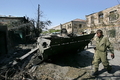 グルジア・南オセチア（South Ossetia）自治州の州都ツヒンバリ（Tskhinvali）で、破壊された戦車のそばを歩く同自治州の兵士（2008年8月10日撮影）。(c)AFP/DMITRY KOSTYUKOV