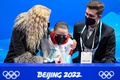 北京冬季五輪、フィギュアスケート女子シングル・フリースケーティング（FS）。キスアンドクライで涙するロシア五輪委員会（ROC）のカミラ・ワリエワ（中央）を慰めるコーチのエテリ・トゥトベリーゼ氏（左、2022年2月17日撮影）。(c)Manan VATSYAYANA / AFP 