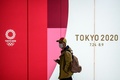 都内の地下鉄駅で、マスクをしながら東京五輪のロゴの前を歩く人（2020年3月11日撮影）。(c)Philip FONG / AFP