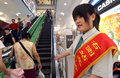「列に並ぶ日」の2007年6月11日、北京市のショッピングモールで、エスカレーターでは左側を空けるよう呼びかける店員。(c)AFP/TEH ENG KOON