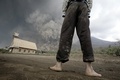 インドネシアの北スマトラ（North Sumatra）州カロ（Karo）で、シナブン山（Mount Sinabung）の噴火に伴う巨大な火山灰雲を村から見つめる住民（2014年2月1日撮影）。(c)AFP/Chaideer MAHYUDDIN