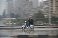 突然の寒波に見舞われたエジプトの首都カイロ（Cairo）で、雨の中をスクーターに乗って走る人たち。郊外ではここ数年で初めての降雪が観測された（2013年12月13日撮影）。(c)AFP/KHALED DESOUKI