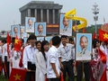 ベトナム・ハノイ（Hanoi）で行われた軍事パレードを終え、ホー・チ・ミン（Ho Chi Minh）の肖像を手にホーチミン廟前を歩く学生たち（2010年10月10日撮影）。(c)AFP/HOANG DINH Nam