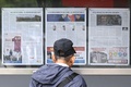 韓国ソウル市の街頭で、北朝鮮軍によるウクライナ紛争への派兵決定に関する報道を読む男性（2024年10月21日撮影）。(c) Anthony WALLACE / AFP