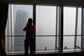 中国・北京で、スモッグに覆われた建物の写真を撮る男性（2017年1月1日撮影）。(c)AFP/GREG BAKER