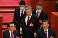 中国・北京の人民大会堂で行われた中国共産党第20回大会閉幕式で、習近平国家主席（右）と李克強首相（左）が席に着く中、介添えを受けて席に向かう胡錦濤前国家主席（中央、2022年10月22日撮影）。(c)Noel CELIS / AFP
