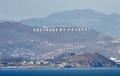 黄海の北方限界線付近にある韓国・延坪（Yeonpyeong）島から眺めた、北朝鮮西岸。丘の中腹には、故金日成（キム・イルソン、Kim Il-Sung）国家主席をたたえるスローガンが掲げられている（2010年1月28日撮影、資料写真）。(c)AFP/KIM JAE-HWAN