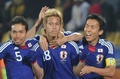 2010年サッカーW杯南アフリカ大会（%%2010 World Cup%%）1次リーグE組、デンマーク対日本。日本は3-1で勝利し、勝ち点6（2勝1敗）の同組2位で決勝トーナメントに進んだ。日本の決勝トーナメント進出は、自国開催以外のW杯では初めて。写真は前半17分に先制点を決め、チームメイトから祝福される日本の本田圭佑（%%Keisuke Honda%%、中央）。（2010年6月24日撮影）(c)AFP/GABRIEL BOUYS
