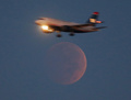 米首都ワシントンD.C.（Washington D.C.）で、月食の最中に満月のそばを飛び去る飛行機（2014年10月8日撮影）。(c)AFP/Getty Images/Mark Wilson