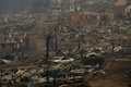 チリのサンタ・オルガで、山火事で全焼した町の中を通過するチリ国旗を掲げた車（2017年1月26日撮影）。(c)AFP/PABLO VERA LISPERGUER