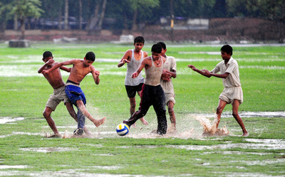 雨と波に踏ん張る少年、モンスーン期のインド