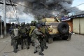 イスラム武装勢力の襲撃を受けたフィリピン南部ミンダナオ（Mindanao）島の商業都市サンボアンガ（Zamboanga）では、12日も治安当局と和平協議に応じないイスラム反政府勢力との戦いが2か所の戦線で続いている。同国政府は、炎に包まれた複数の地区を奪還した。

サンボアンガでは、4日間にわたる戦闘で数千人が避難を強いられている。フィリピン軍報道官によると、同市のサンタカタリナ（Santa Catalina）地区では、治安部隊が進軍する中、家々が炎に包まれた。

警察の支援を受けた少なくとも1500人の兵士が、サンボアンガ郊外のイスラム教徒が多く住む6地区を包囲。これらの地域では、反政府勢力「モロ民族解放戦線（MNLF）」のメンバー約180人が、9日に攻撃を開始して以降潜伏を続けている。反政府勢力は数十人の人々を「人間の盾」にしているため、市民が負傷することを避けたい治安部隊との間でこう着状態が続いている。

写真はサンボアンガで、煙を上げる家々の近くで反政府勢力への攻撃に備える兵士ら（2013年9月12日撮影）。(c)AFP/TED ALJIBE