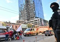 ウクライナの首都キーウで、ロシアの攻撃により破損したオフィスビルの近くに立つ警官（2022年10月10日撮影）。(c)Sergei SUPINSKY / AFP