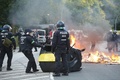 ドイツ北部ハンブルクで行われた、主要20か国・地域（G20）に抗議するデモの現場で、燃やされたごみ容器を片付ける機動隊（2017年7月6日撮影）。(c)AFP/Odd ANDERSEN