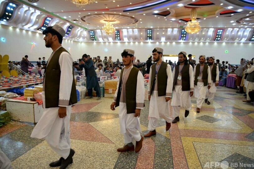 会場に並ぶ新郎とケーキ アフガニスタンで集団結婚式