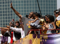 08-09NBAファイナルを制したロサンゼルス・レイカーズ（%%Los Angeles Lakers%%）の優勝パレードが17日、ロサンゼルス（Los Angeles）で行われ、数万人ものバスケットボールファンが祝福のため、市内中心部に詰めかけた。レイカーズの本拠地ステープルズ・センター（Staples Center）から始まったパレードは、8万人のファンが待つロサンゼルス・メモリアル・コロシアム（Los Angeles Memorial Coliseum）まで行われ、数百人の警察官が動員され。写真はバスからファンの声援に応えるレイカーズのコービー・ブライアント（%%Kobe Bryant%%）。（2009年6月17日撮影）(c)AFP/Getty Images/Stephen Dunn