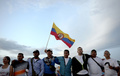 コロンビア西部エルディアマンテにある「コロンビア革命軍（FARC）」のキャンプで、大画面で放映された和平協定調印式典の様子を見守ったFARCメンバーら（2016年9月26日撮影）。(c)AFP/RAUL ARBOLEDA