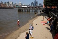 英ロンドンのテムズ川のほとりで涼を取る人（2022年6月17日撮影）。(c)CARLOS JASSO / AFP
