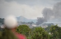 フィリピン南部ミンダナオ島のマラウィ市で、軍のヘリコプターがイスラム過激派組織の拠点にロケット弾を撃ち込んだ後、市場付近から立ち上る煙を見る住民（2017年5月25日撮影）。(c)AFP/TED ALJIBE