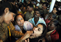 インド・ハイデラバード（Hyderabad）で8日、Bathini Goudさんによる「魚療法（Fish Medicine）」が行われ、投薬を受けるために全国から数千人が集まった。「魚療法」はぜんそくなどの気管支系疾患に効くとして、同国南部に暮らすこの一家が158年前から代々行っている療法で、薬草から作られた秘伝の薬を生きた魚にくわえさせ、順番に患者の口の中に落としていくというもの。投薬は6月のモンスーン到来とともに訪れる縁起の良い日「Mrigasira Karti」に行われる。写真は、患者に投薬するBathini Goudさんの家族（左、2009年6月8日撮影）。(c)AFP/Noah SEELAM
