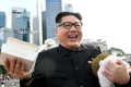 シンガポールでドリアンとチキンライスを手に笑顔を見せる金正恩（キム・ジョンウン）朝鮮労働党委員長のそっくりさんのハワードXさん（2018年5月27日撮影）。(c)AFP/Roslan RAHMAN