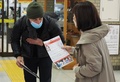 栃木県日光市の駅でティフェヌ・ベロンさんの情報提供を求めて通行人にビラを配る兄のダミアンさん（左、2022年12月13日撮影）。(c)Toshifumi KITAMURA / AFP