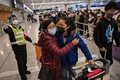 隔離措置撤廃後の中国・上海浦東国際空港国際便到着ゲート外で到着客（右）を歓迎する女性（2023年1月7日撮影）。(c)Hector RETAMAL / AFP