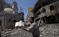 イスラエル軍による攻撃で大きな被害を受けたパレスチナ自治区ガザ地区（Gaza Strip）のモスクの近くで、手にしたイスラム教の聖典コーランを開いて見せるパレスチナ人の男性（2014年7月23日撮影）。(c)AFP/MAHMUD HAMS