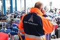 荷物仕分け機器が故障したフランス・オルリ空港で、荷物カートの横で電話で話す空港職員（2023年8月3日撮影）。(c)STEFANO RELLANDINI / AFP