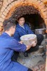 建甌市東峰鎮坤口村で生地を窯に入れる黄綱興さんと息子の黄祥鑫さん（2024年12月20日撮影）。(c)Xinhua News