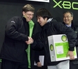 日本におけるXbox発売初日に東京で、最初の購入者となった神奈川県から来た男性（中央）と握手するマイクロソフト（Microsoft）のビル・ゲイツ（Bill Gates）会長（左、2002年2月22日撮影）。(c)AFP/JEFF CHRISTENSEN