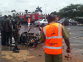 ナイジェリアの首都アブジャ（Abuja）の警察本部で、自爆攻撃による爆発の被害を受けた車を調べる警官（2011年6月16日撮影）。(c)AFP/NEMA