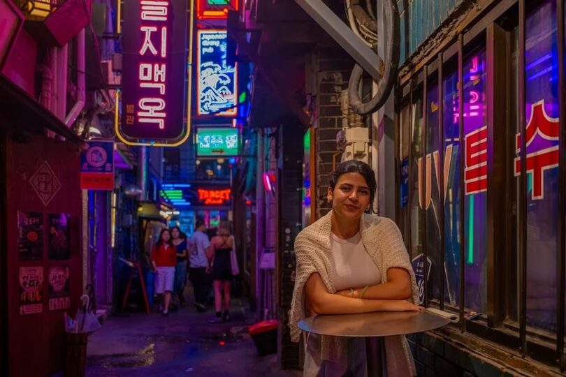 ネオンサインや看板を背景に写真を撮る旅行者＝ソウル観光財団提供(c)news1