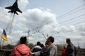 ウクライナ東部クラマトルスク（Kramatorsk）で、装甲車を取り囲む親ロシア派の活動家らの上空を飛ぶウクライナ軍の戦闘機（2014年4月16日撮影）。(c)AFP/ANATOLIY STEPANOV